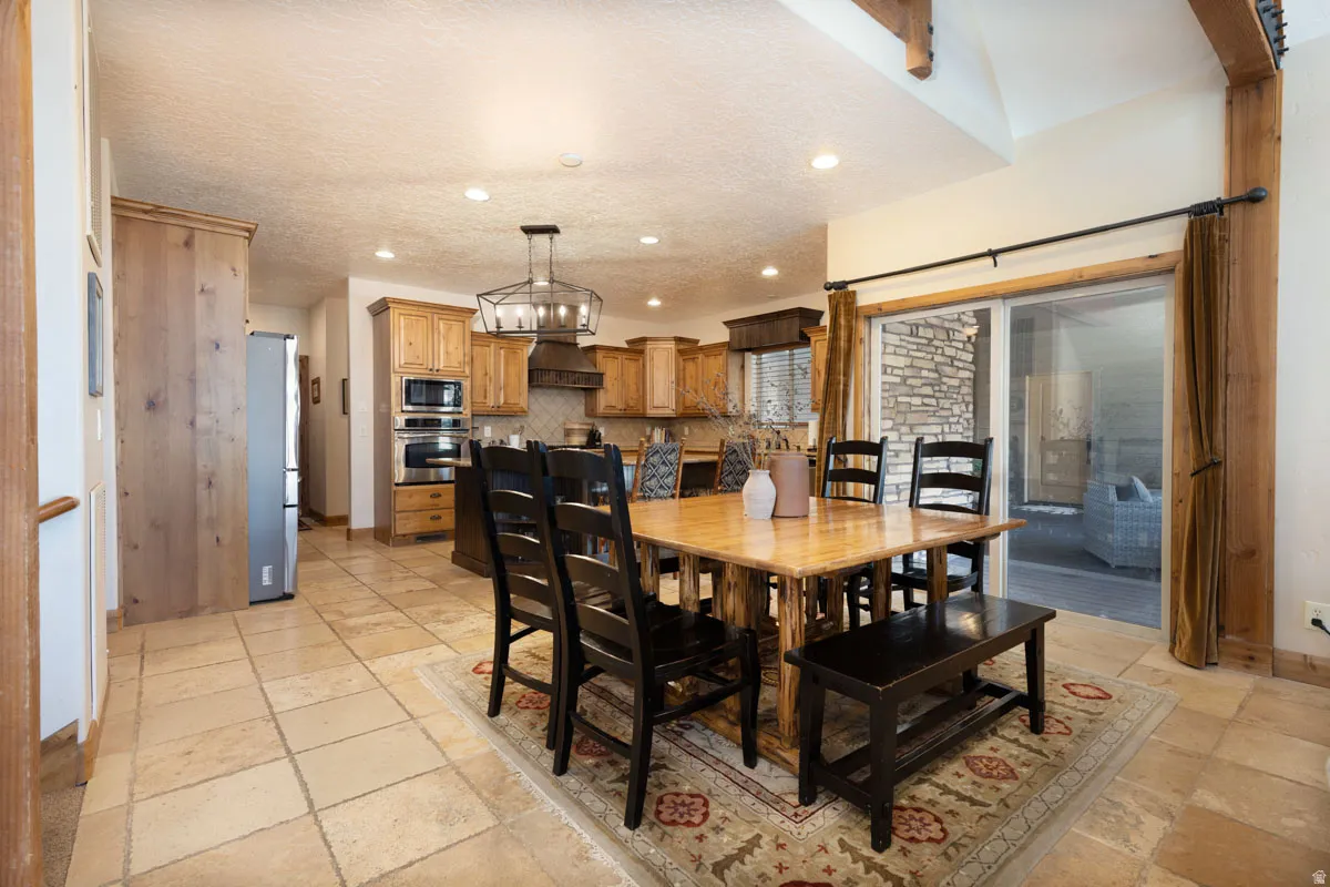 Open-concept kitchen and dining area featuring wood cabinetry, stainless steel appliances, recessed lighting, and tile flooring
