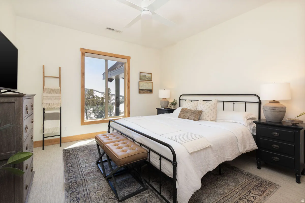 Bright room featuring a large window with wood-finish trim, neutral wall color, and a ceiling fan