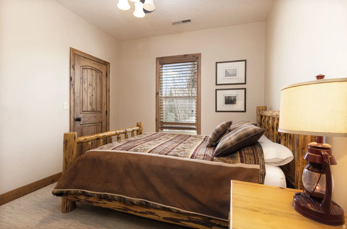 Carpeted room featuring a rustic wood-finish door, matching trim, and a window with wood-finish blinds