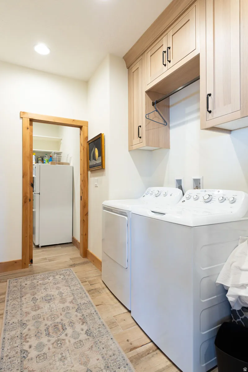 Laundry area with light wood-finish cabinetry featuring black hardware and an integrated hanging rod