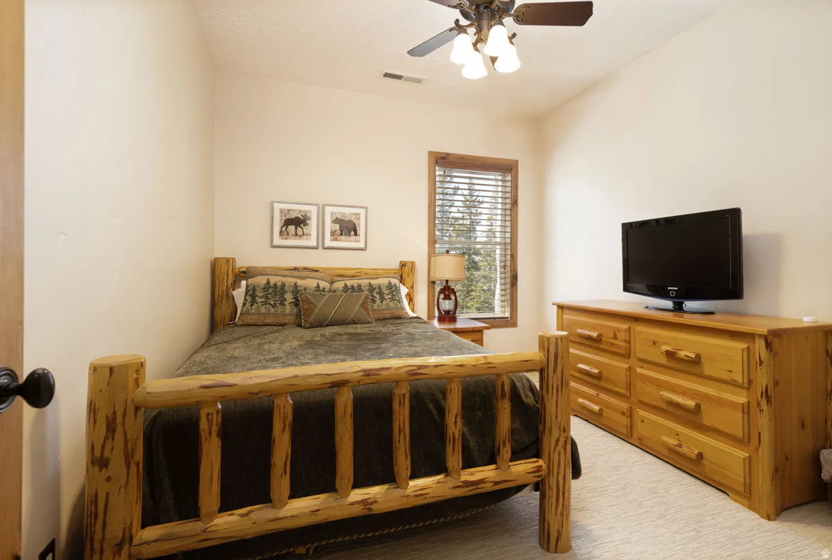 Bedroom featuring neutral wall paint, wood-framed window with blinds, and a ceiling fan with integrated lighting