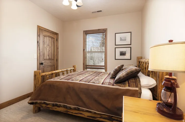 Carpeted room featuring a rustic wood-finish door, matching trim, and a window with wood-finish blinds