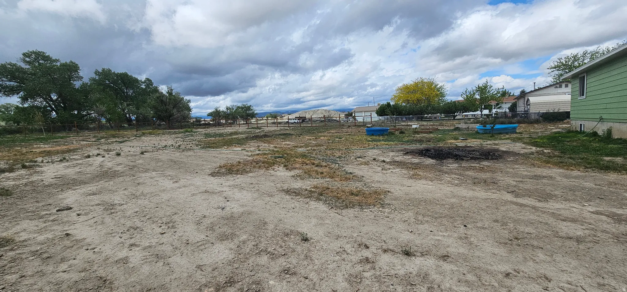 Expansive undeveloped lot featuring a natural ground cover, mature trees along the perimeter, and partial fencing
