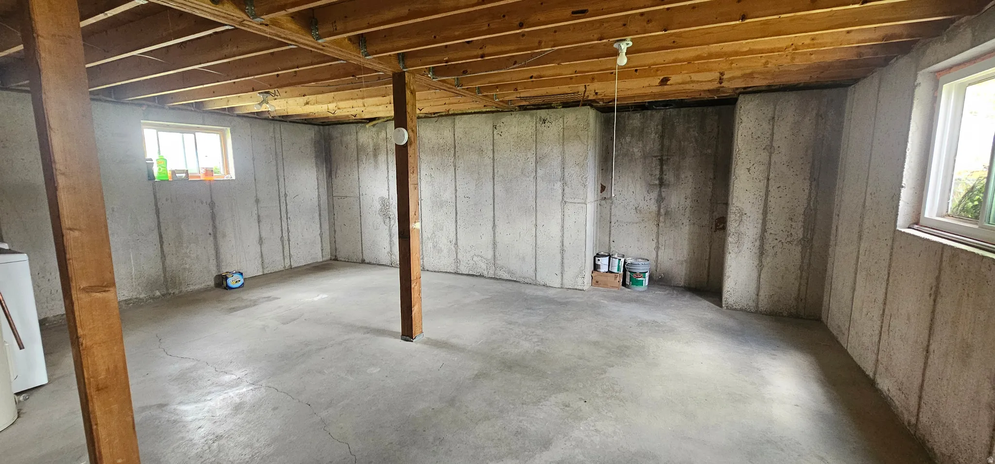 Unfinished basement with concrete flooring and exposed wood ceiling joists