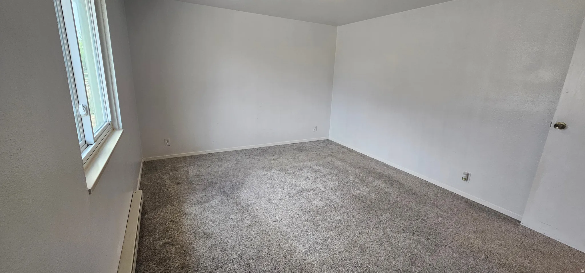Spacious room featuring light gray carpeting and white walls
