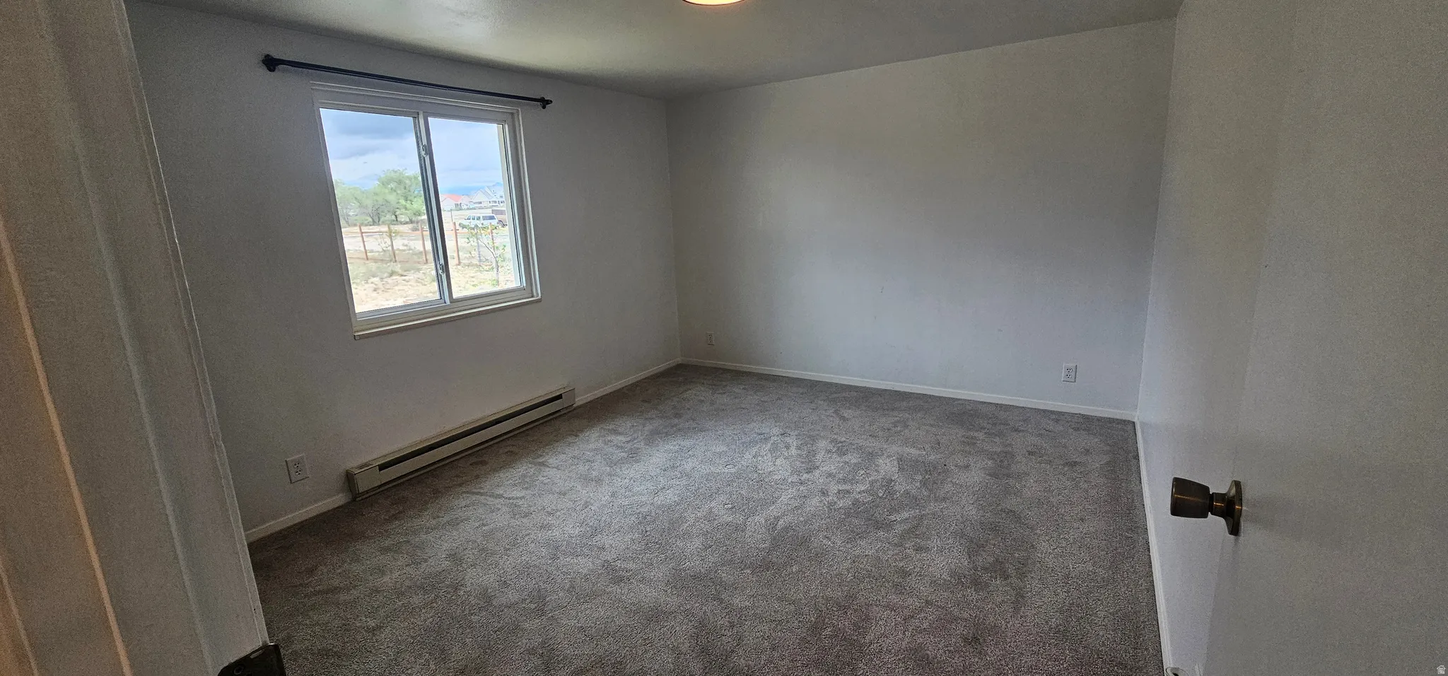 Carpeted room featuring a double-pane window, baseboard heating, and a flush mount light fixture