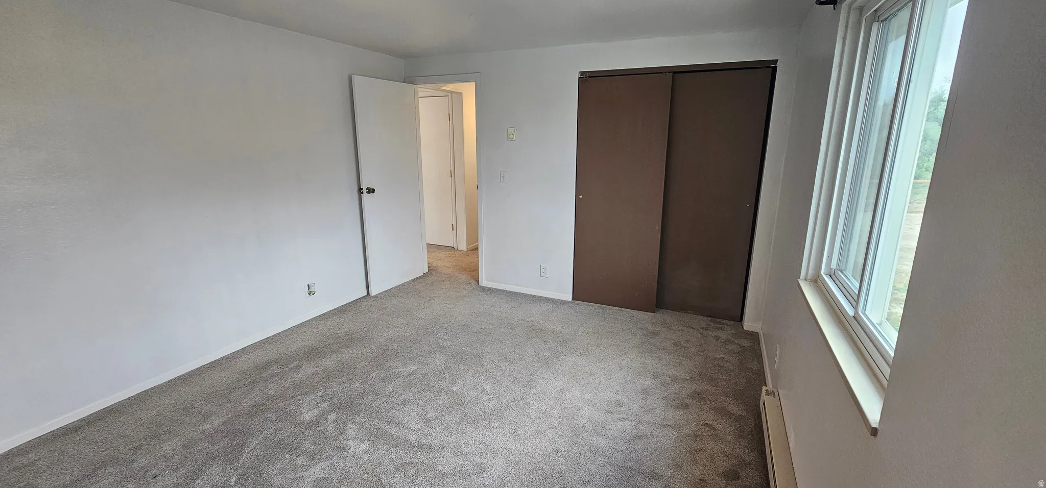 Spacious room with light gray carpeting, neutral wall finishes, and a double-pane window
