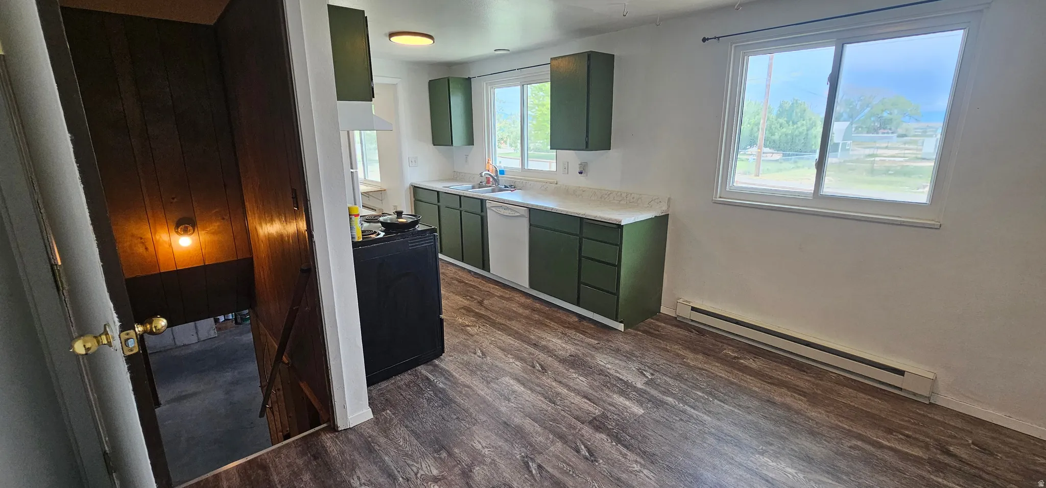 Kitchen featuring wood-finish flooring, green cabinetry, white countertops, and a white dishwasher