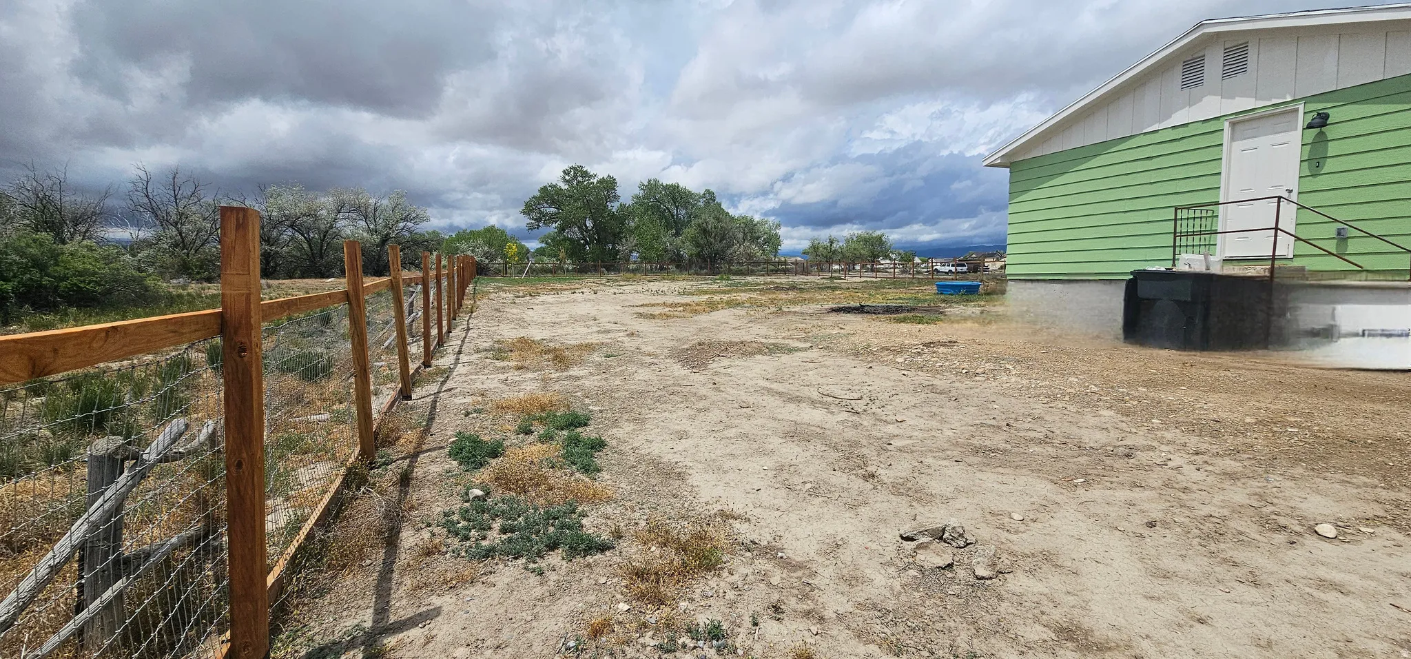 Expansive undeveloped lot with perimeter fencing and a vibrant green siding building