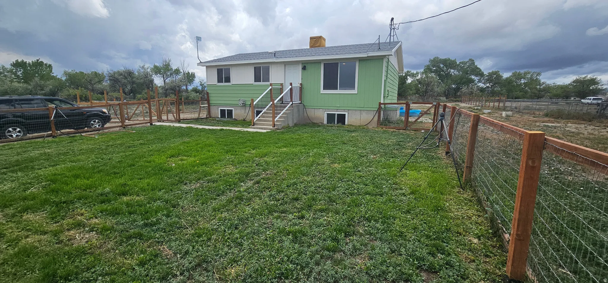 Green siding exterior with white trim, featuring a fenced front yard with grass