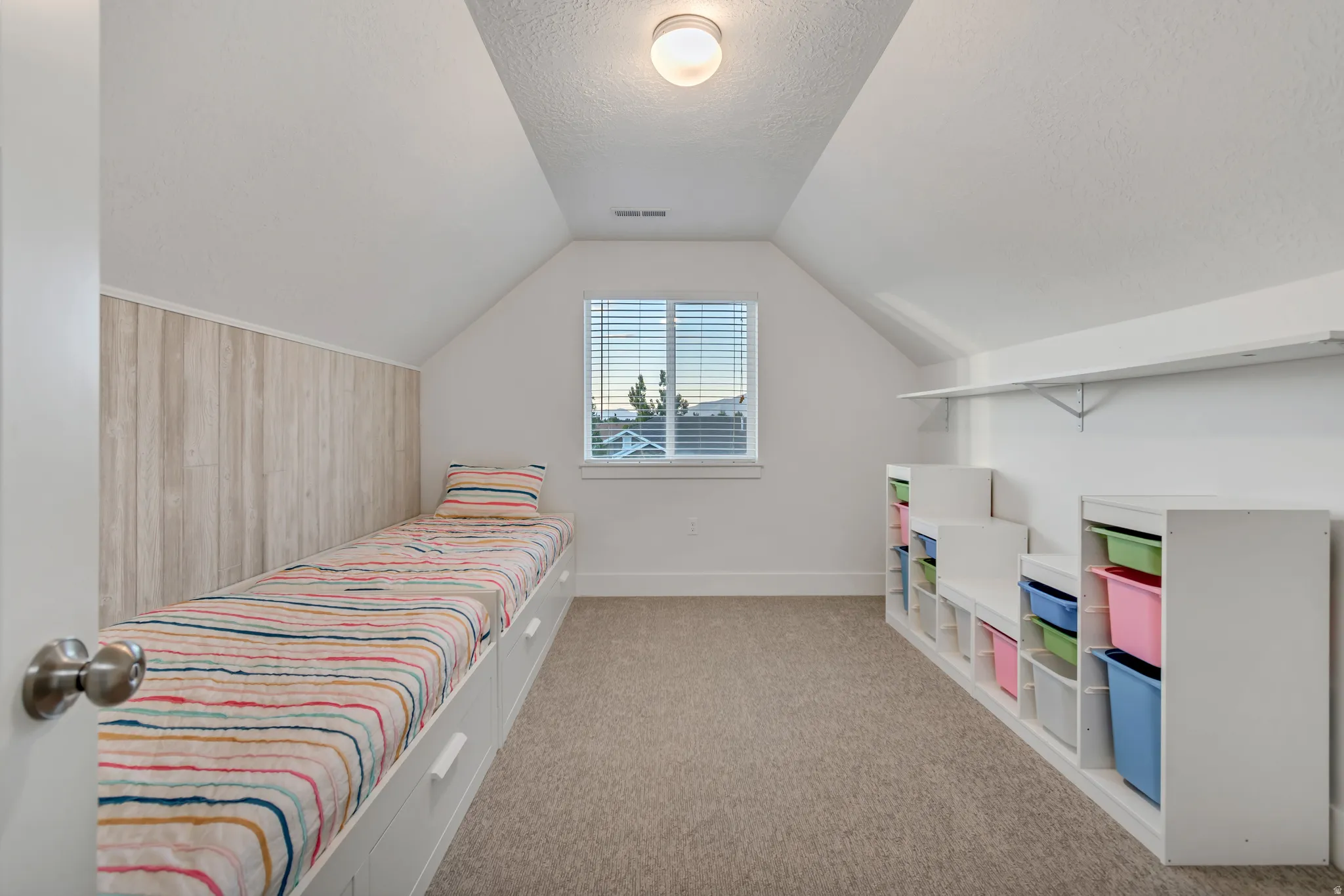 Attic-level room featuring a built-in platform bed with integrated storage drawers