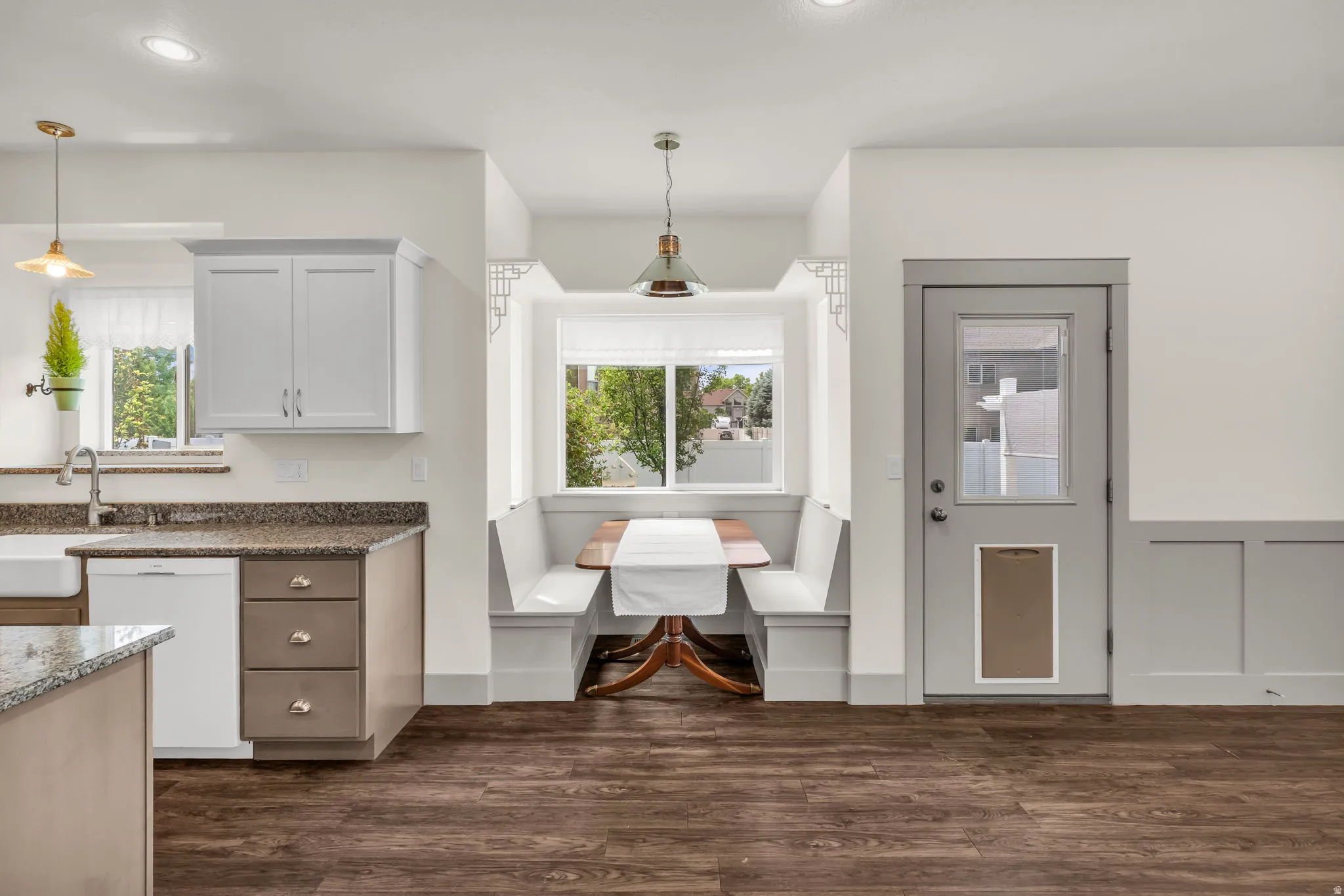 Breakfast nook with built-in bench seating, a wood-finish table, and an overhead pendant light