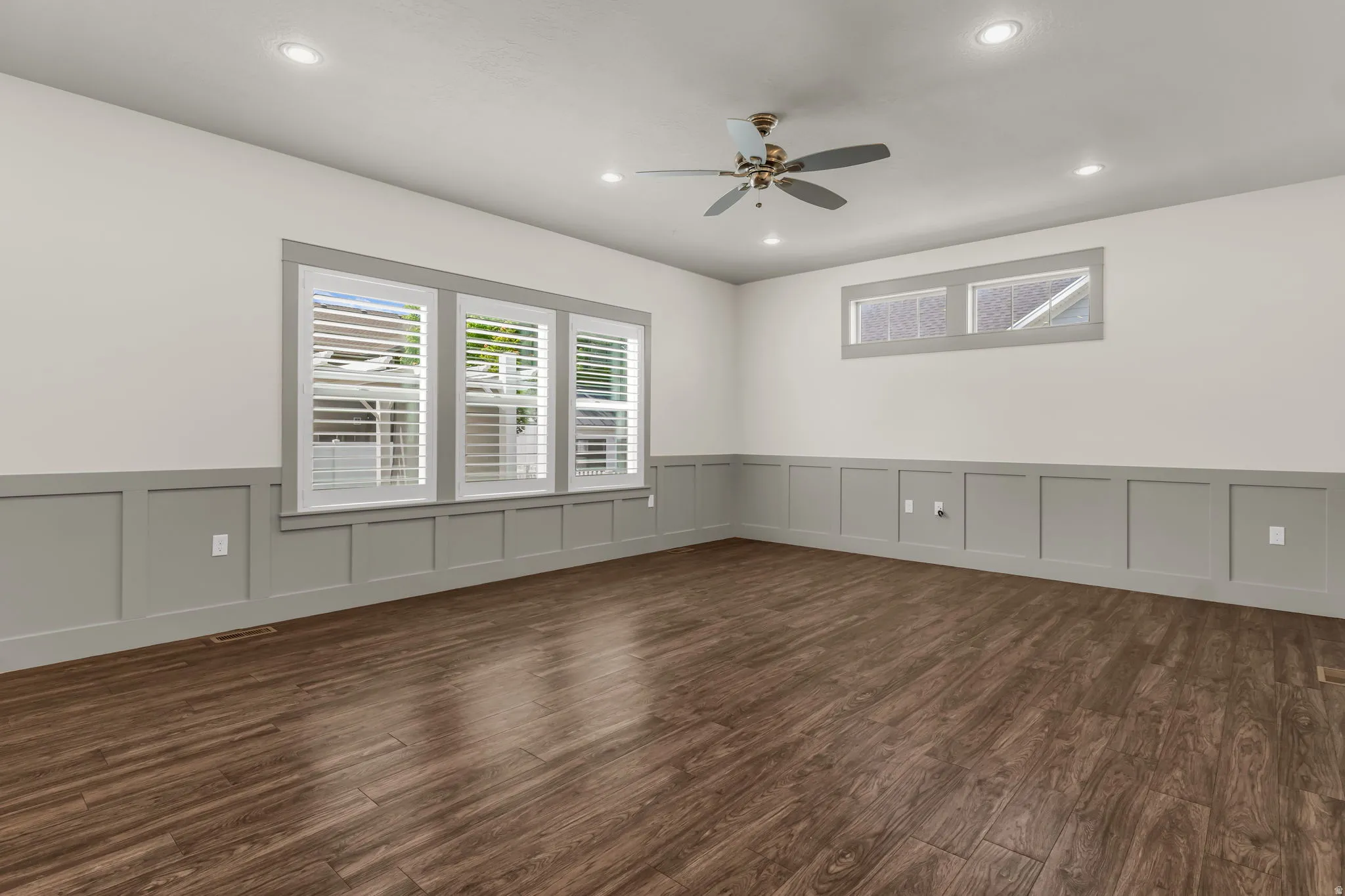Spacious room featuring wood-finish flooring, wainscoting, and recessed lighting