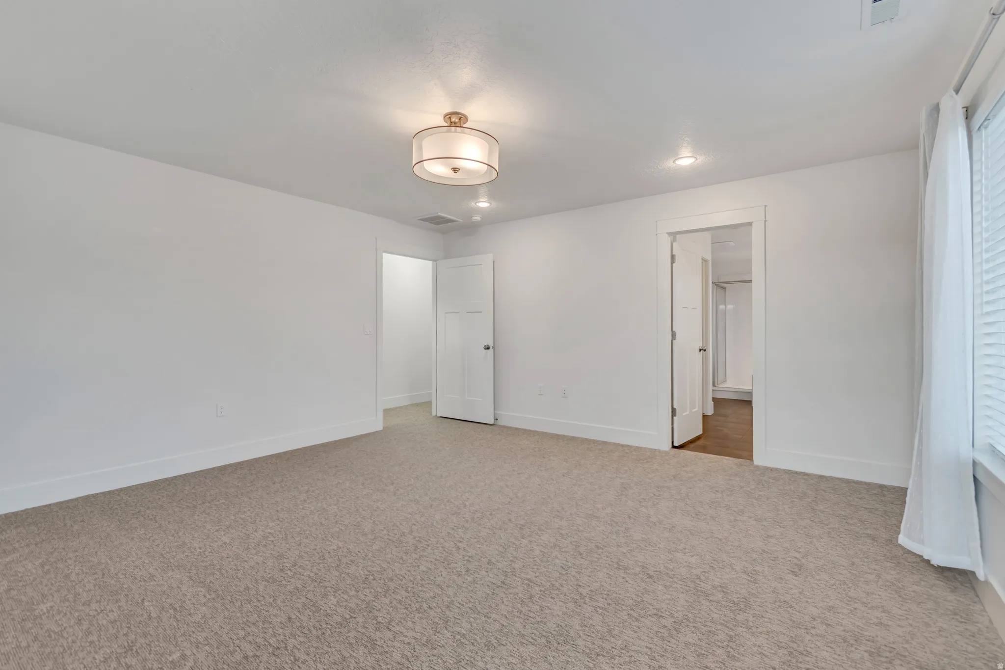 Carpeted room featuring white walls, two interior doors, and a window with blinds