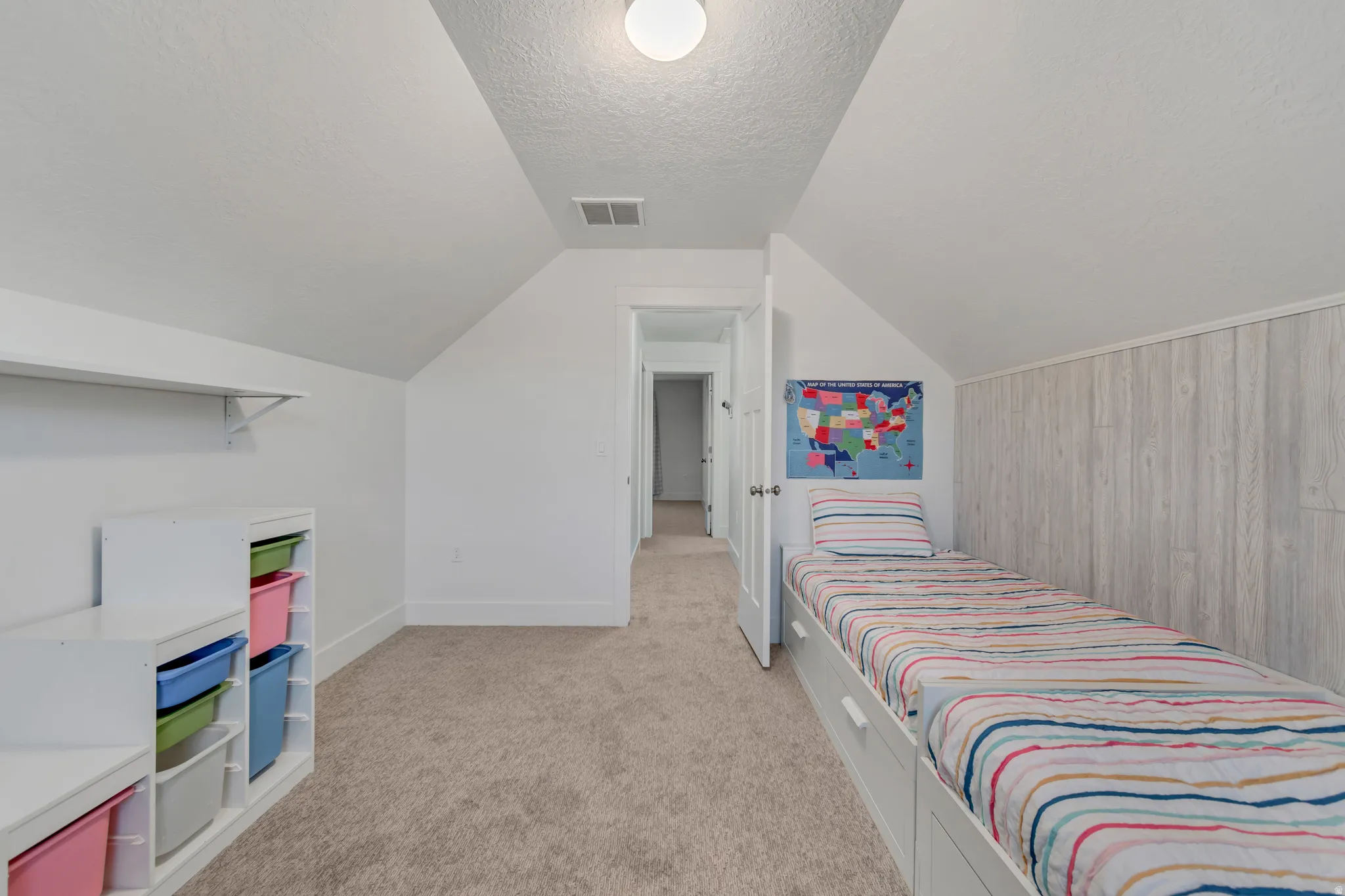 Attic room featuring sloped ceilings, white paneling, and neutral carpeting