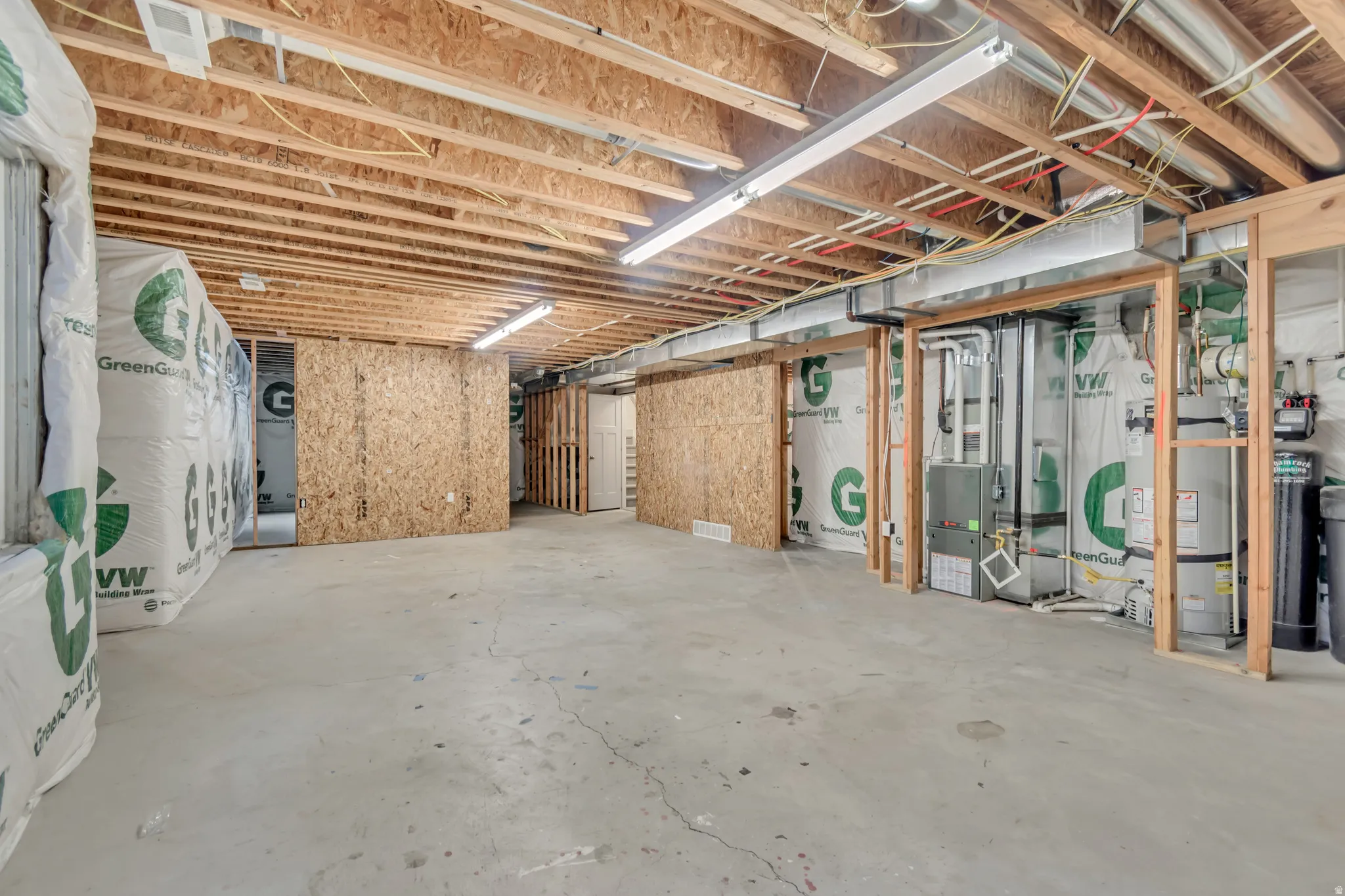 Unfinished basement featuring exposed wood joists, concrete flooring, and utility infrastructure