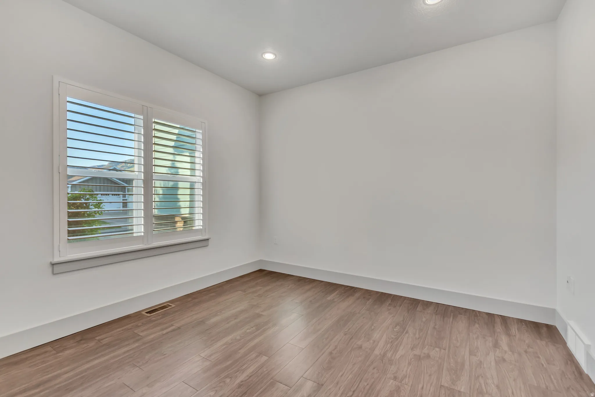 Interior room featuring wood-finish flooring, white walls, and recessed lighting