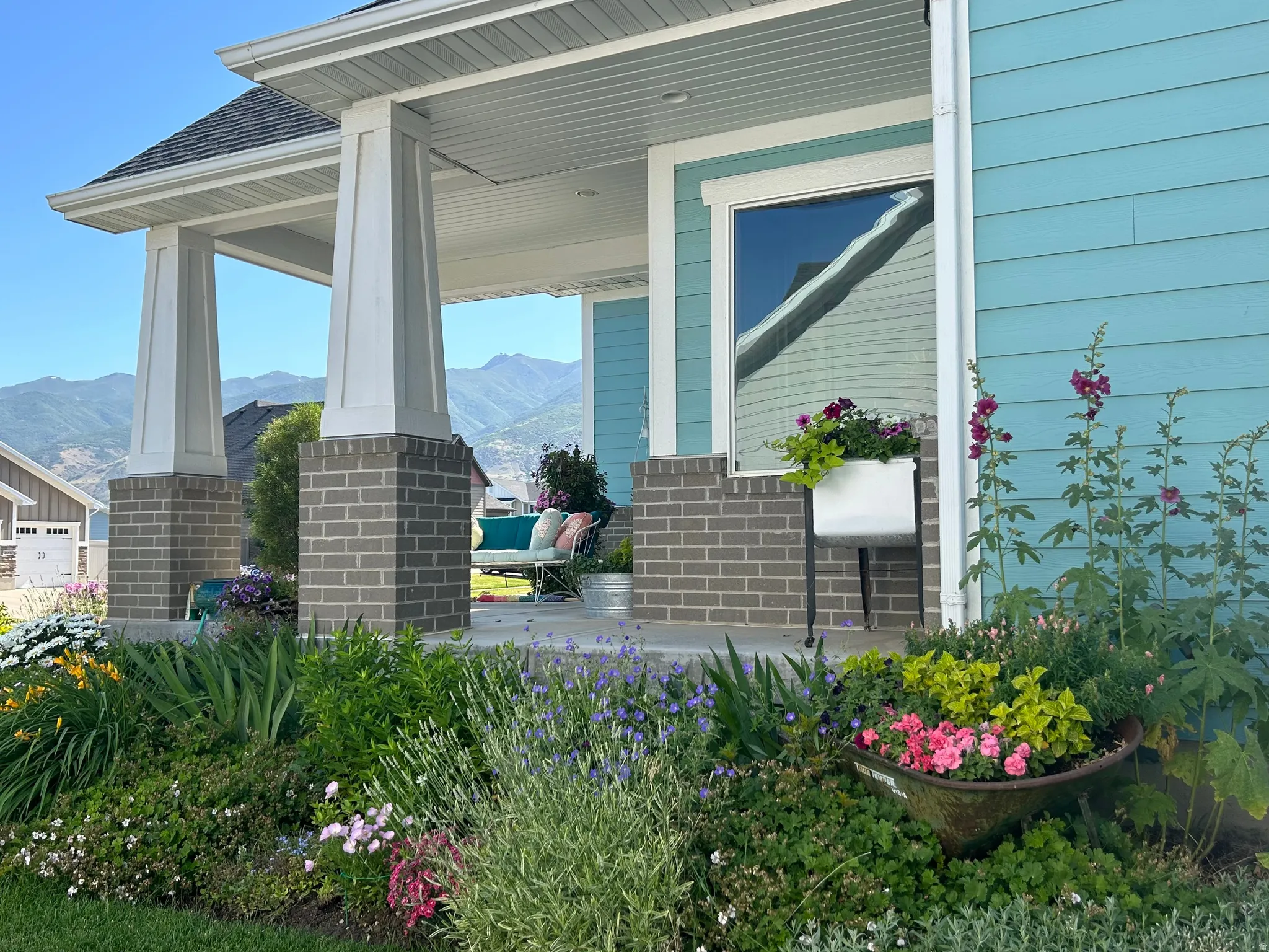 Inviting front porch featuring a light blue siding, white trim, and architectural pillars with brick bases