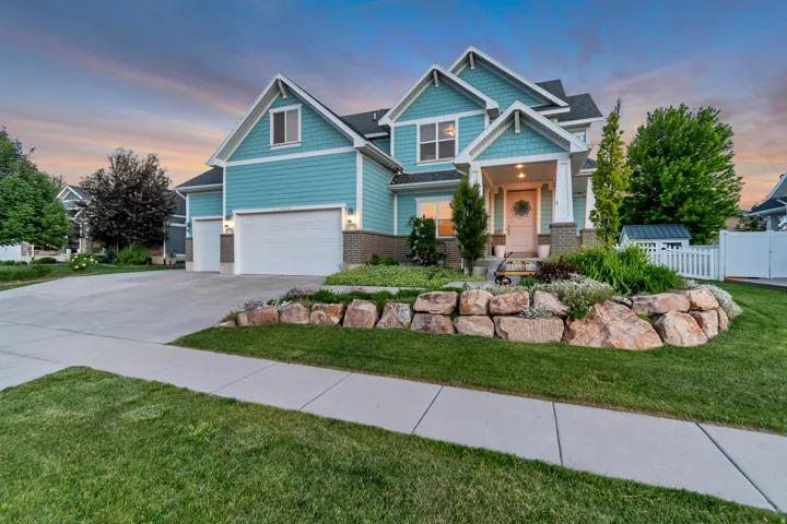 Multi-level residence featuring a teal exterior with white trim, a covered front porch, and a stone-lined garden bed