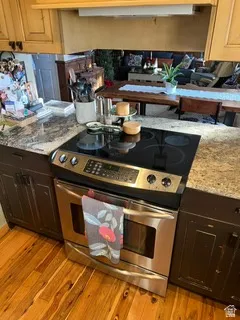 Stainless steel range with a black glass cooktop, set within a granite-finish countertop