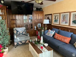 Living space featuring extensive built-in wooden cabinetry, textured wall finish, and a ceiling fan with integrated lighting