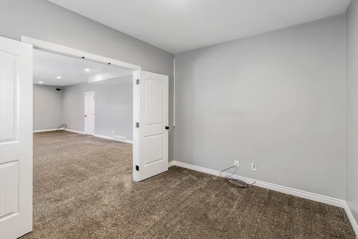 Spacious interior room featuring neutral gray wall paint and plush carpeting
