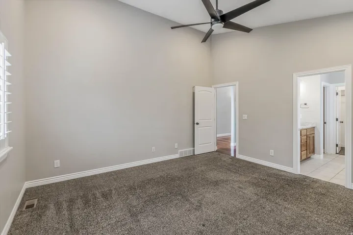 Spacious room featuring vaulted ceilings, a contemporary ceiling fan, and plush carpeting