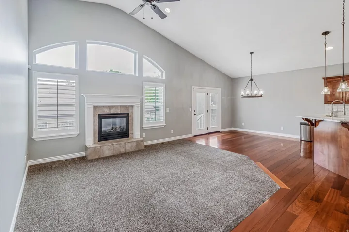 Living area featuring a vaulted ceiling and a fireplace with a stone surround and white mantel