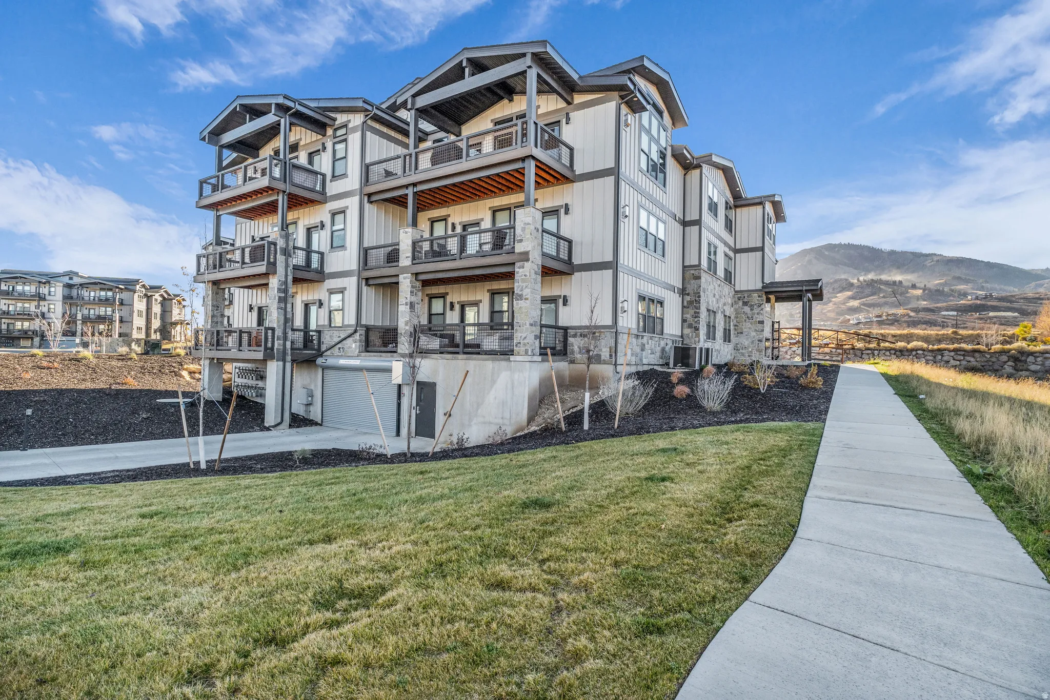 Multi-story residential building featuring a combination of light-colored siding and stone facade