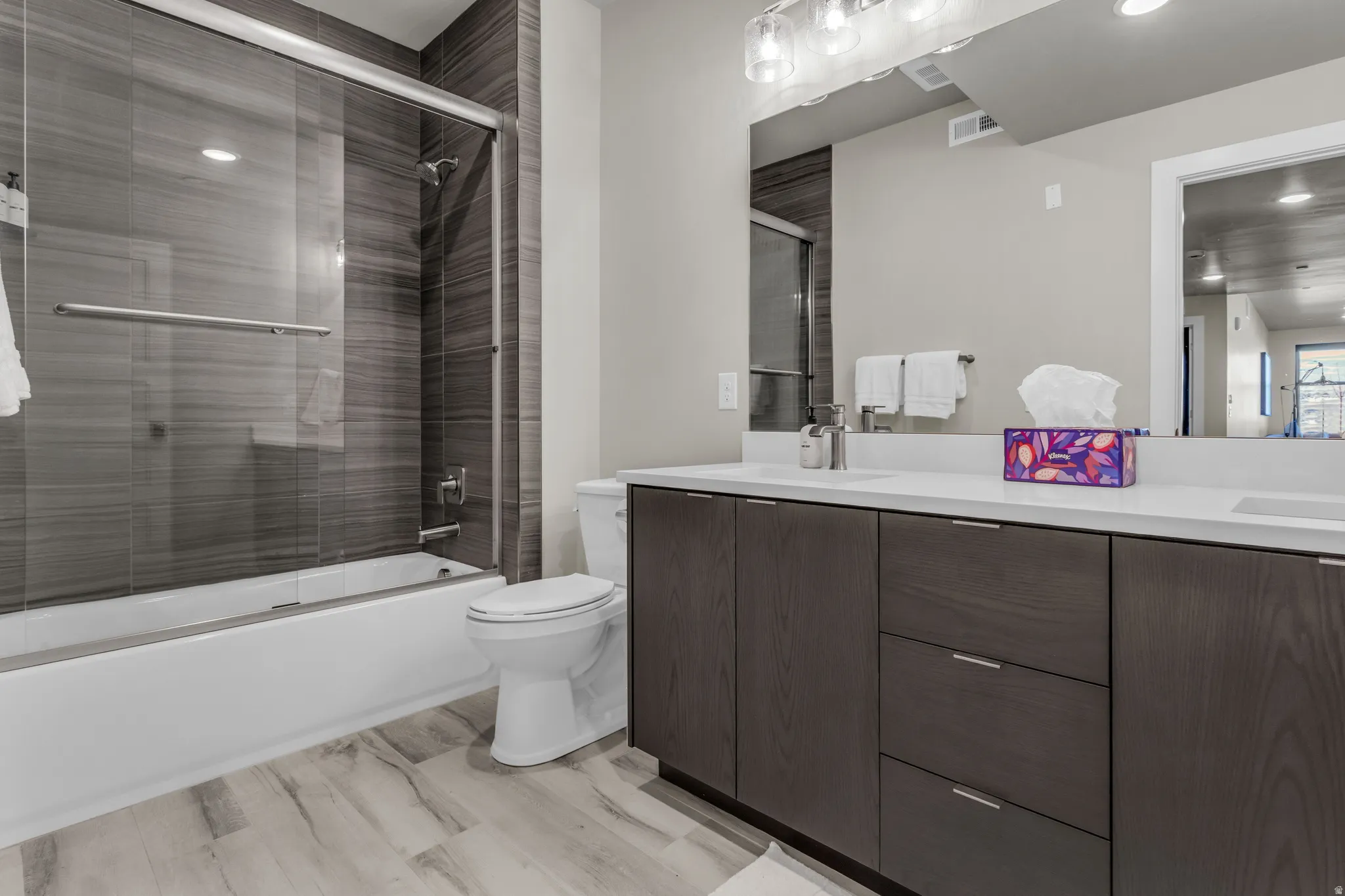 Dual vanity with white countertops, dark wood-finish cabinetry, and contemporary hardware