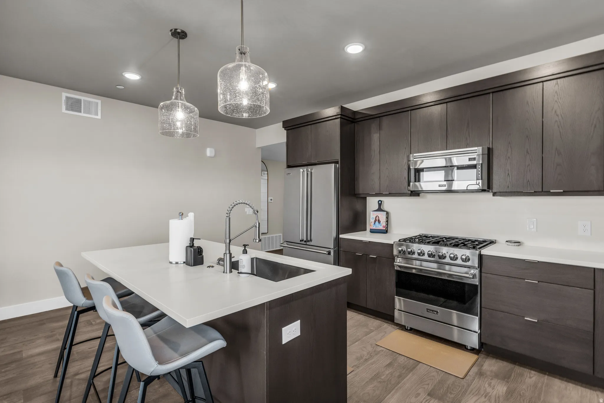 Modern kitchen featuring dark wood-finish cabinetry, stainless steel appliances, and light-toned countertops