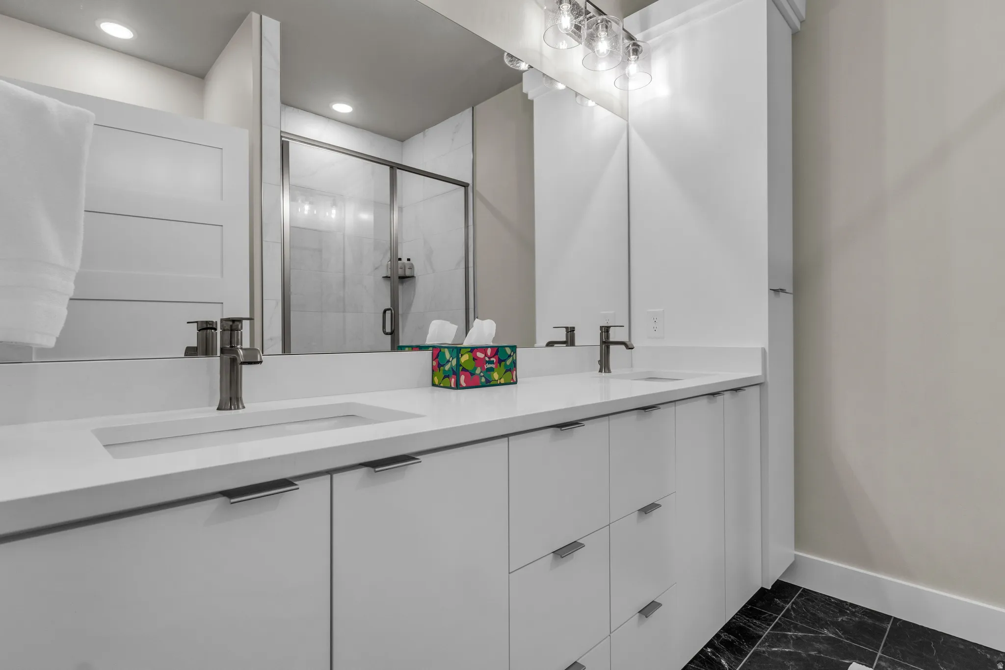 Double vanity with integrated sinks, white cabinetry, and brushed nickel hardware