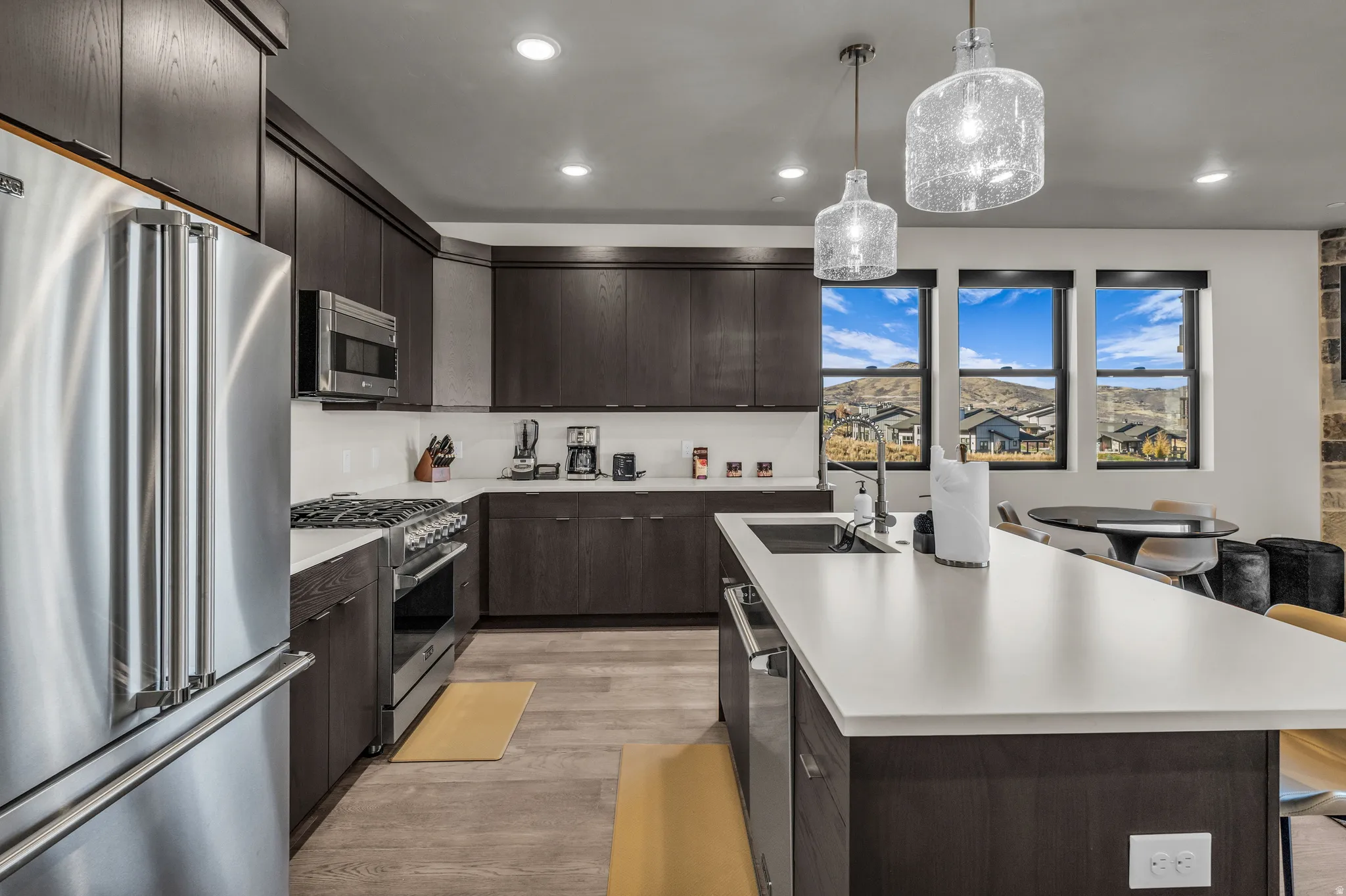 Contemporary kitchen featuring dark wood-finish cabinetry, white countertops, and stainless steel appliances