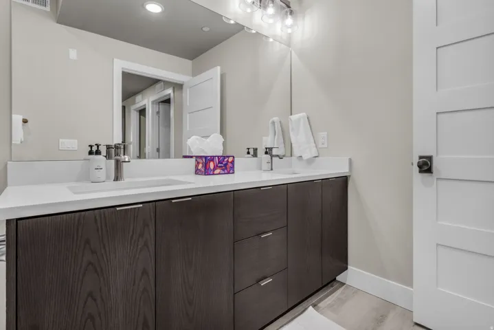Double vanity with integrated sinks, white countertops, dark wood-finish cabinetry, and contemporary brushed nickel fixtures