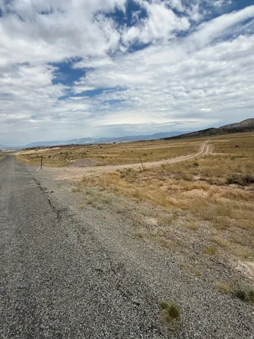 Gravel road extending through open terrain with distant mountains