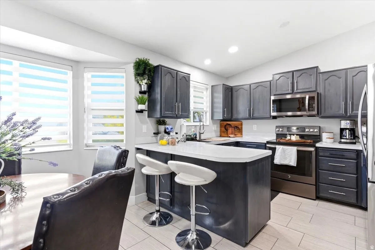 Modern kitchen featuring dark cabinetry, stainless steel appliances, and light-toned countertops