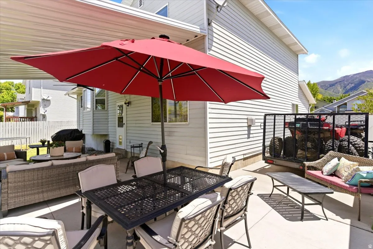 Expansive concrete patio with a covered section and an open-air area, offering direct access to the white vinyl-sided exterior of the property
