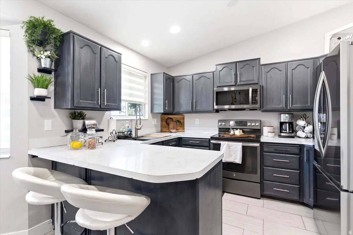 Modern kitchen featuring dark-stained cabinetry, light-toned countertops, and stainless steel appliances