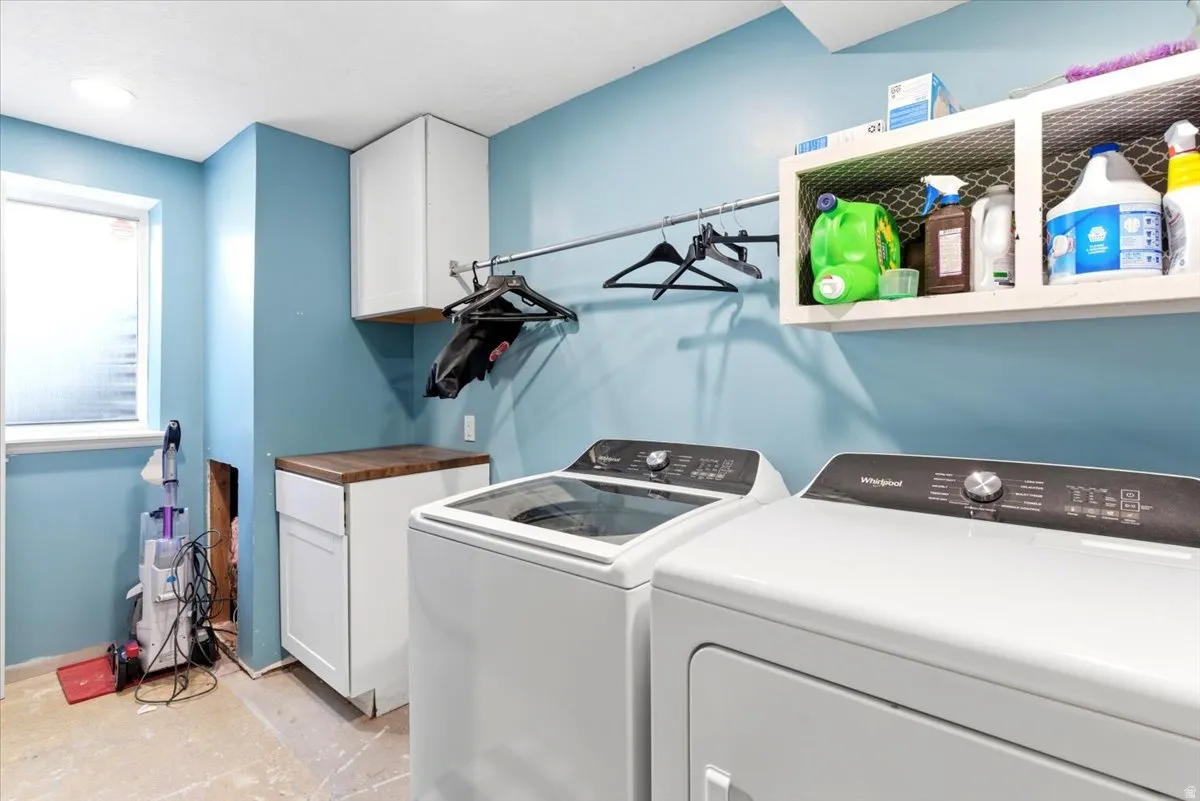 Dedicated laundry area featuring a white base cabinet with a wood-finish countertop