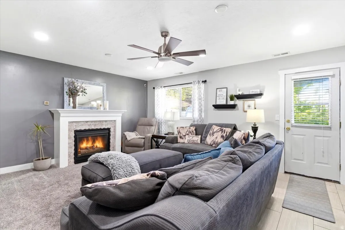 Living area featuring a gas fireplace with a white mantel and stone surround, recessed lighting, and a ceiling fan