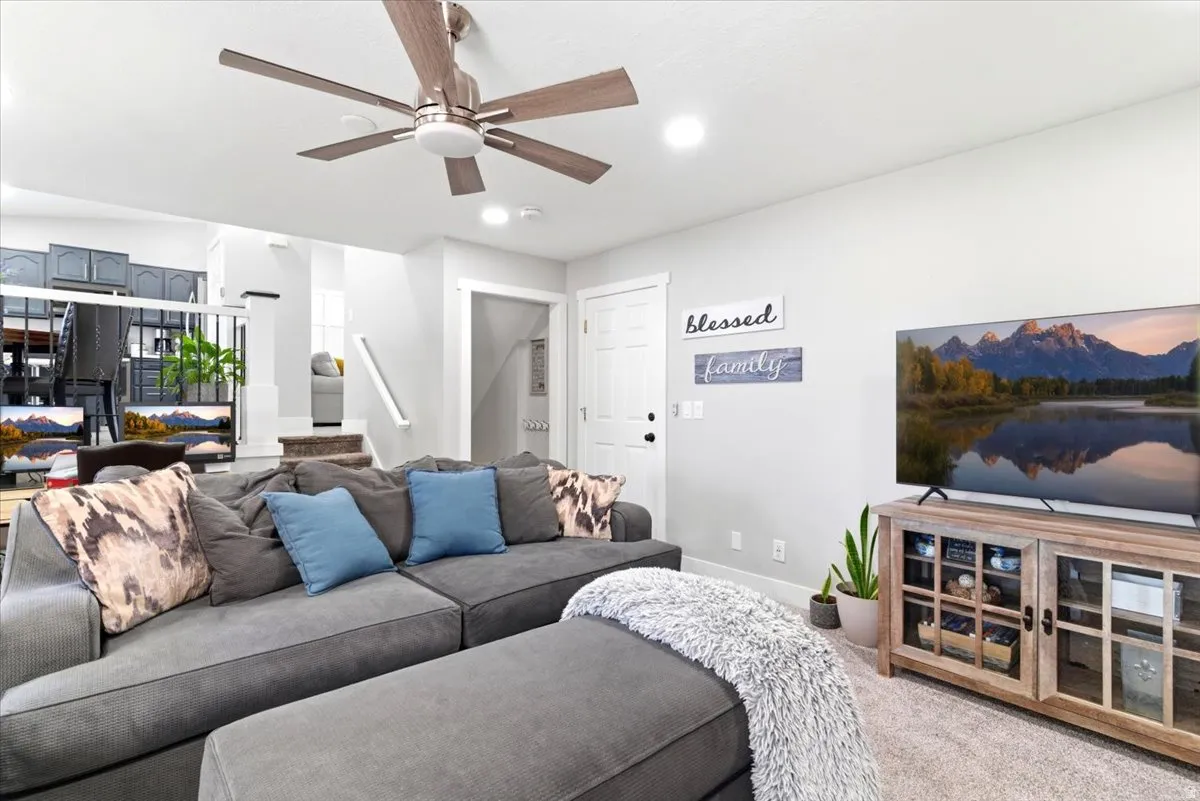 Spacious living area featuring light gray walls, recessed lighting, and a ceiling fan with wood-finish blades