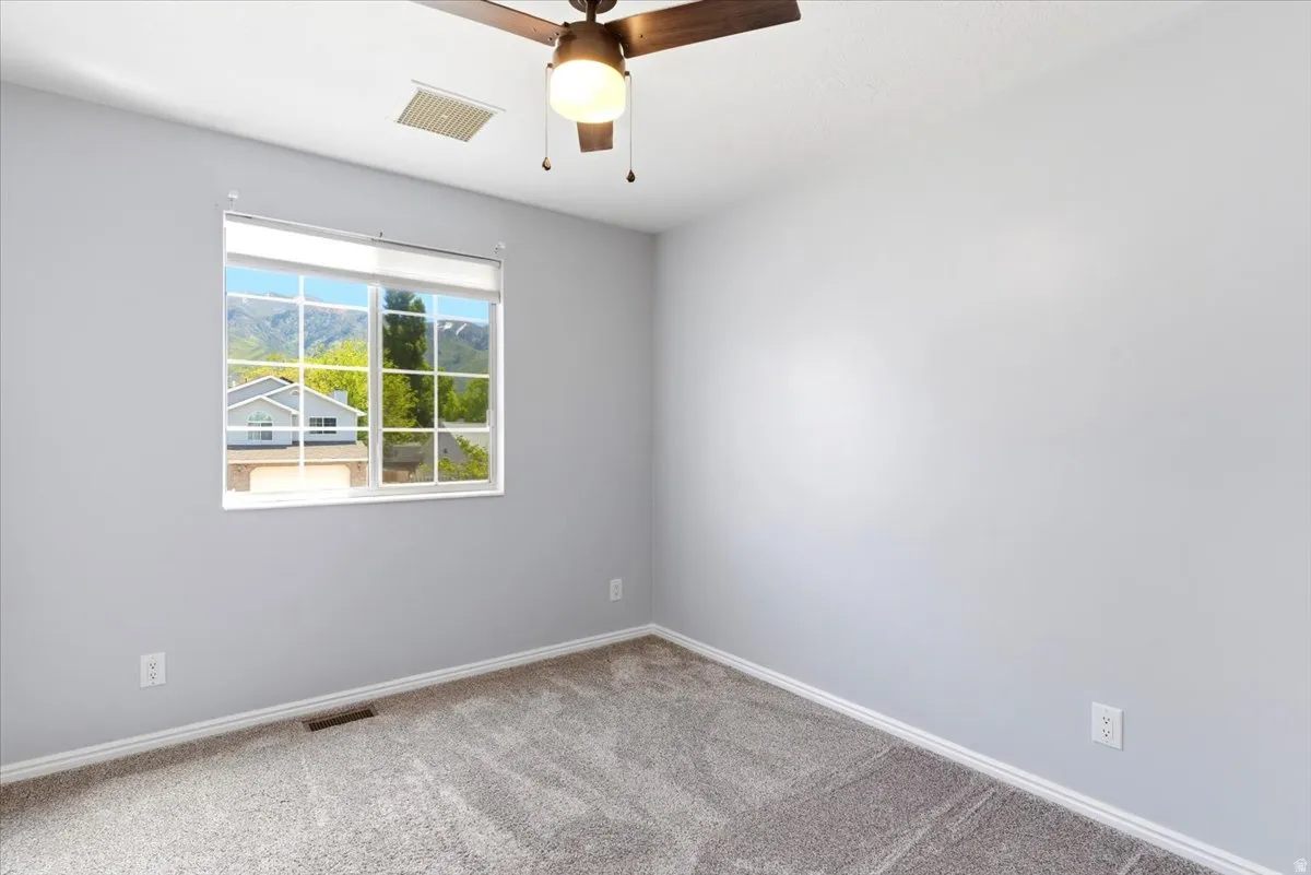 Interior room featuring a large window with mountain scenery, neutral gray walls, and plush carpet flooring