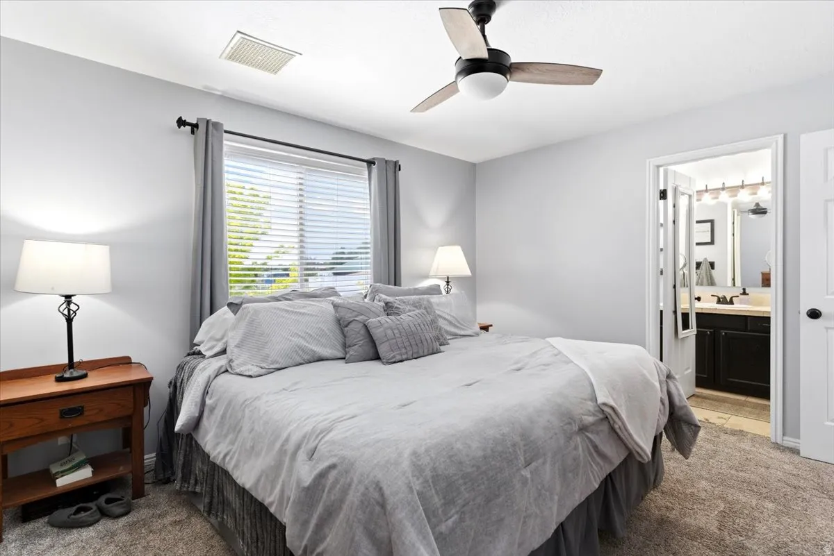 Bedroom featuring light gray walls, textured carpeting, and a ceiling fan with integrated lighting