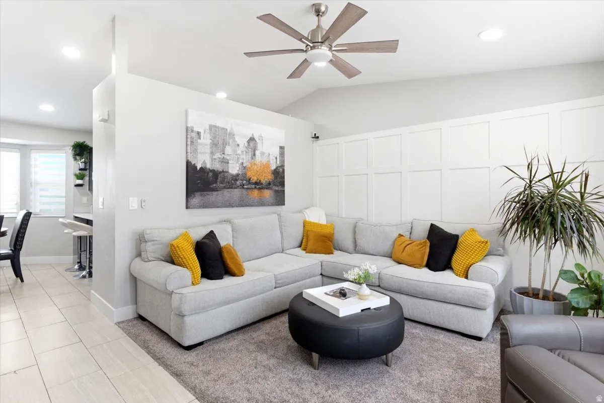 Spacious living area featuring a vaulted ceiling with a modern ceiling fan, recessed lighting, and a decorative paneled accent wall