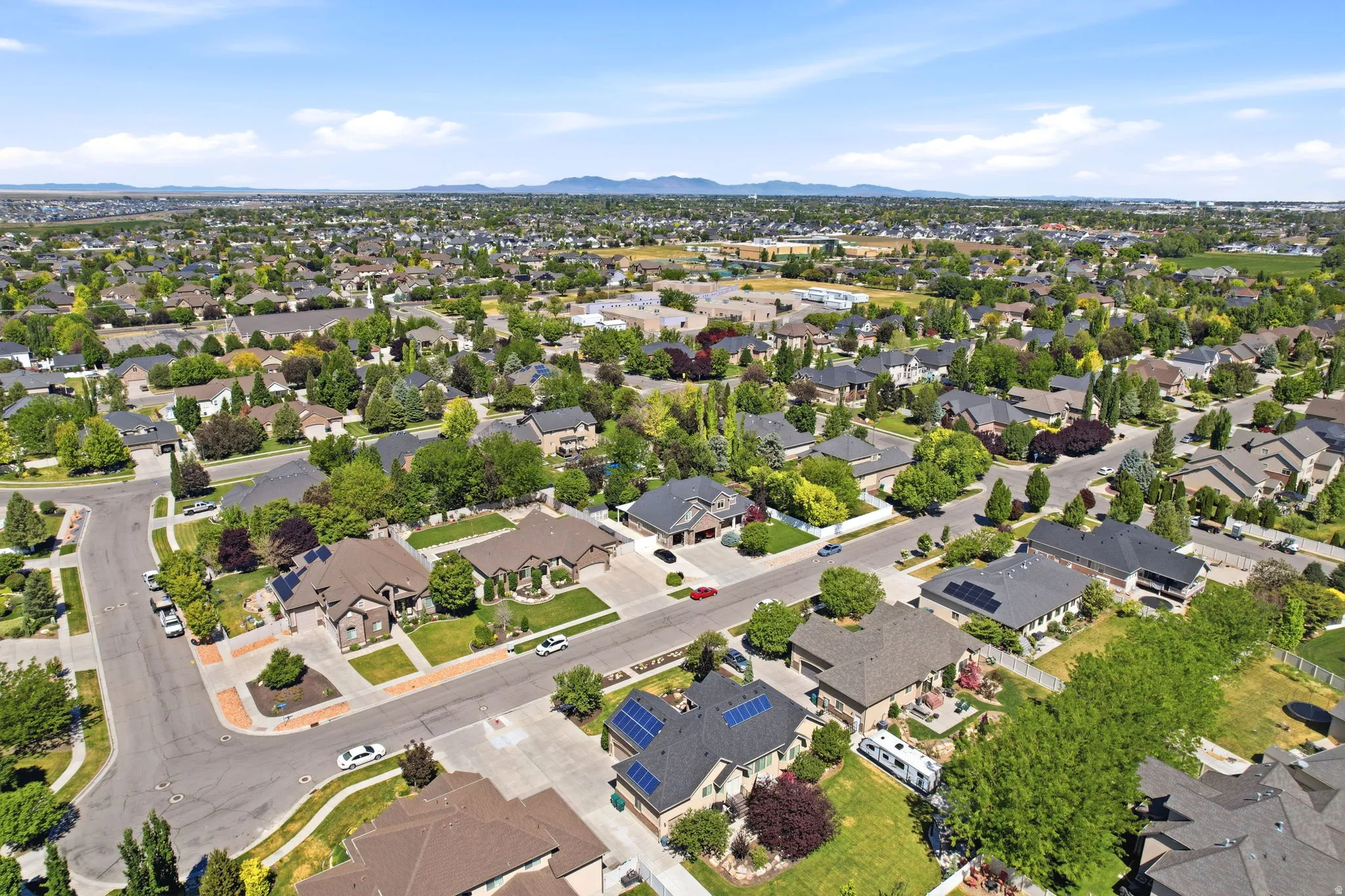 Aerial perspective showcasing a residential neighborhood with numerous single-family homes, mature landscaping, and paved streets