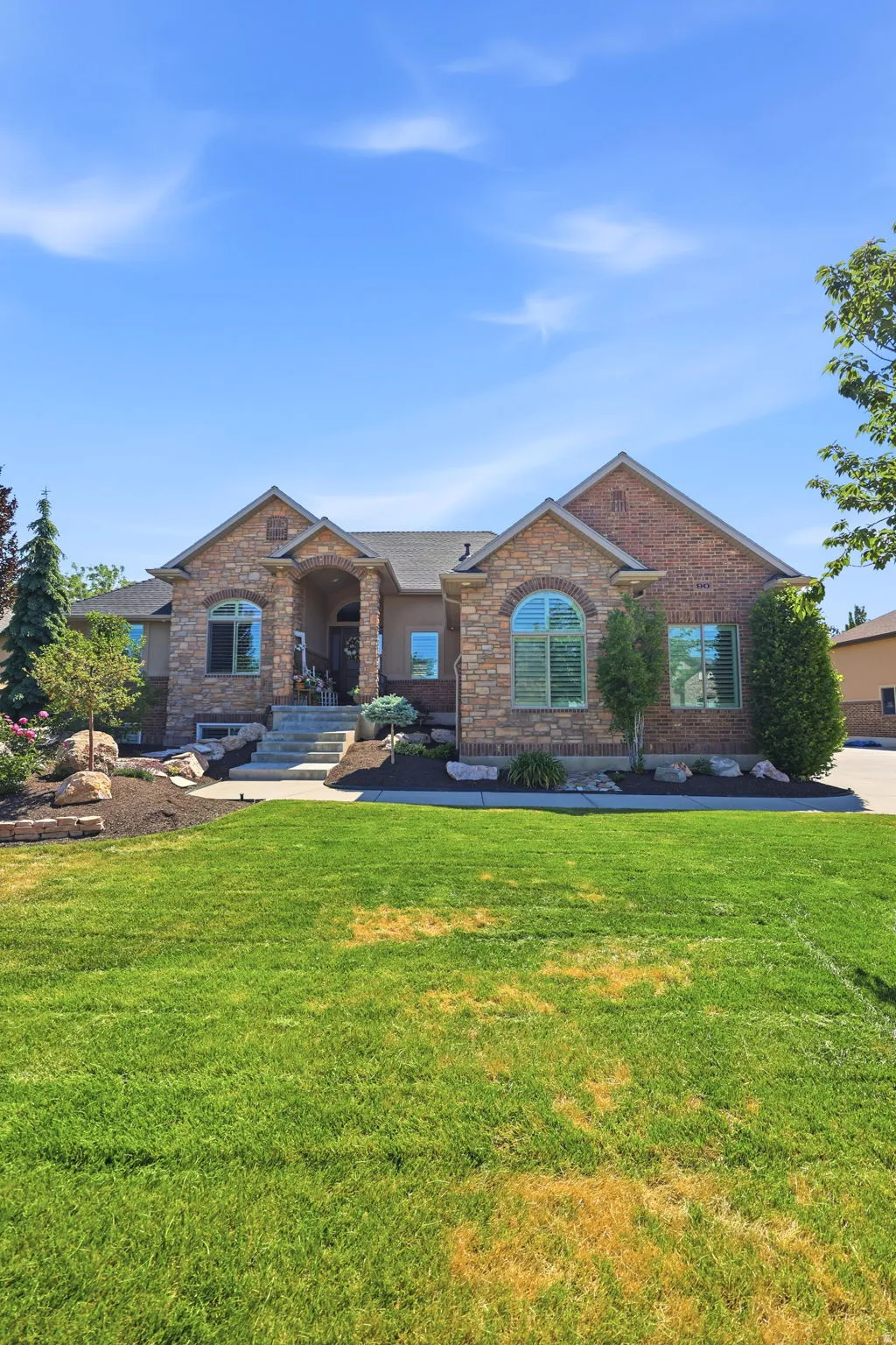 Stone and brick veneer exterior featuring prominent arched windows and a covered front entry