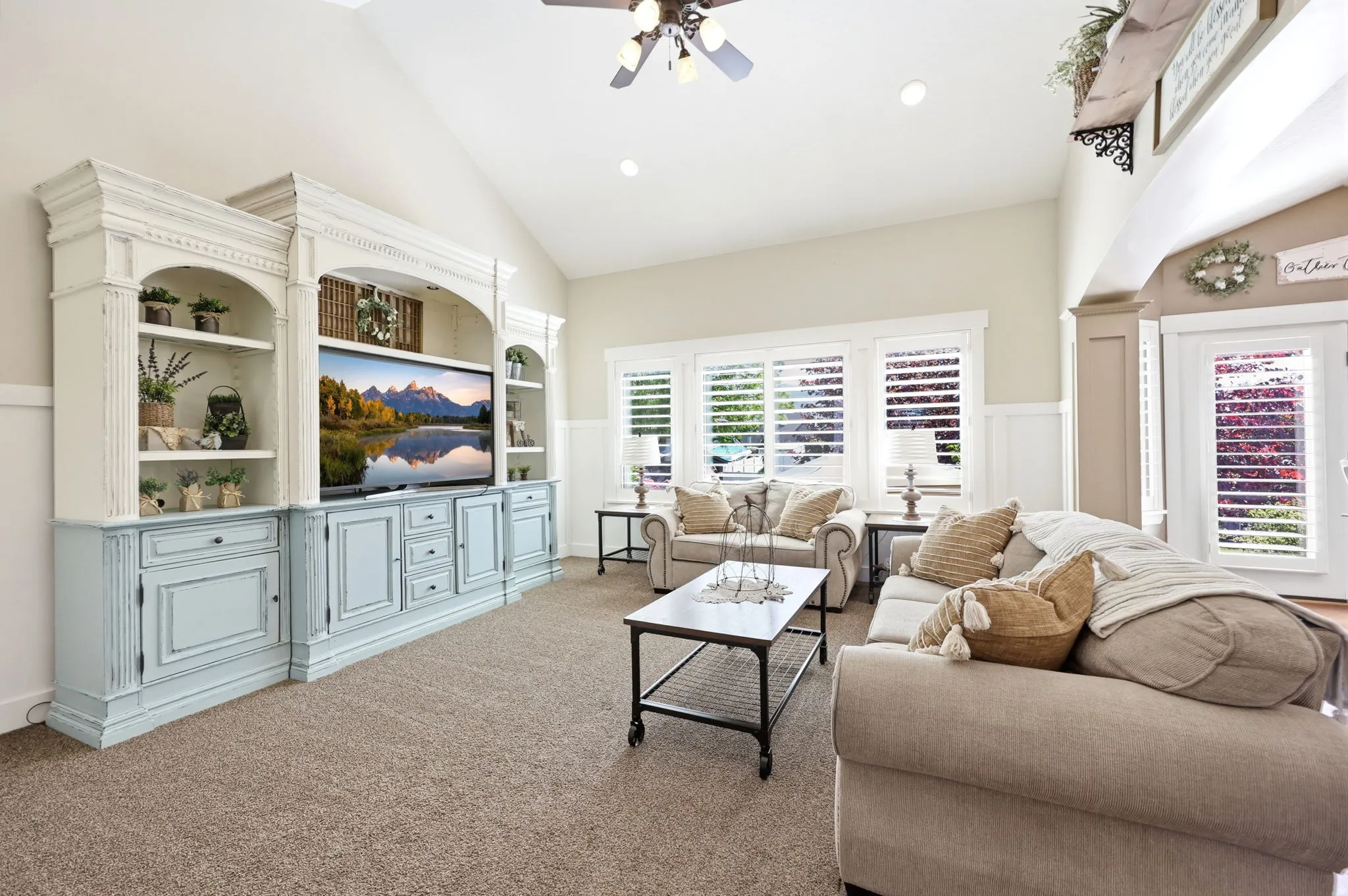 Vaulted ceilings complement the built-in entertainment center featuring distressed white and light blue cabinetry