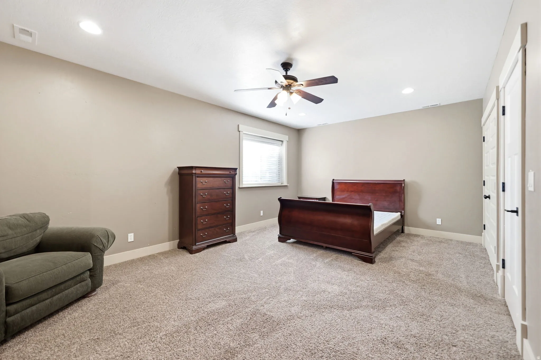 Spacious room featuring neutral carpeting, light-toned walls, and a ceiling fan with integrated lighting