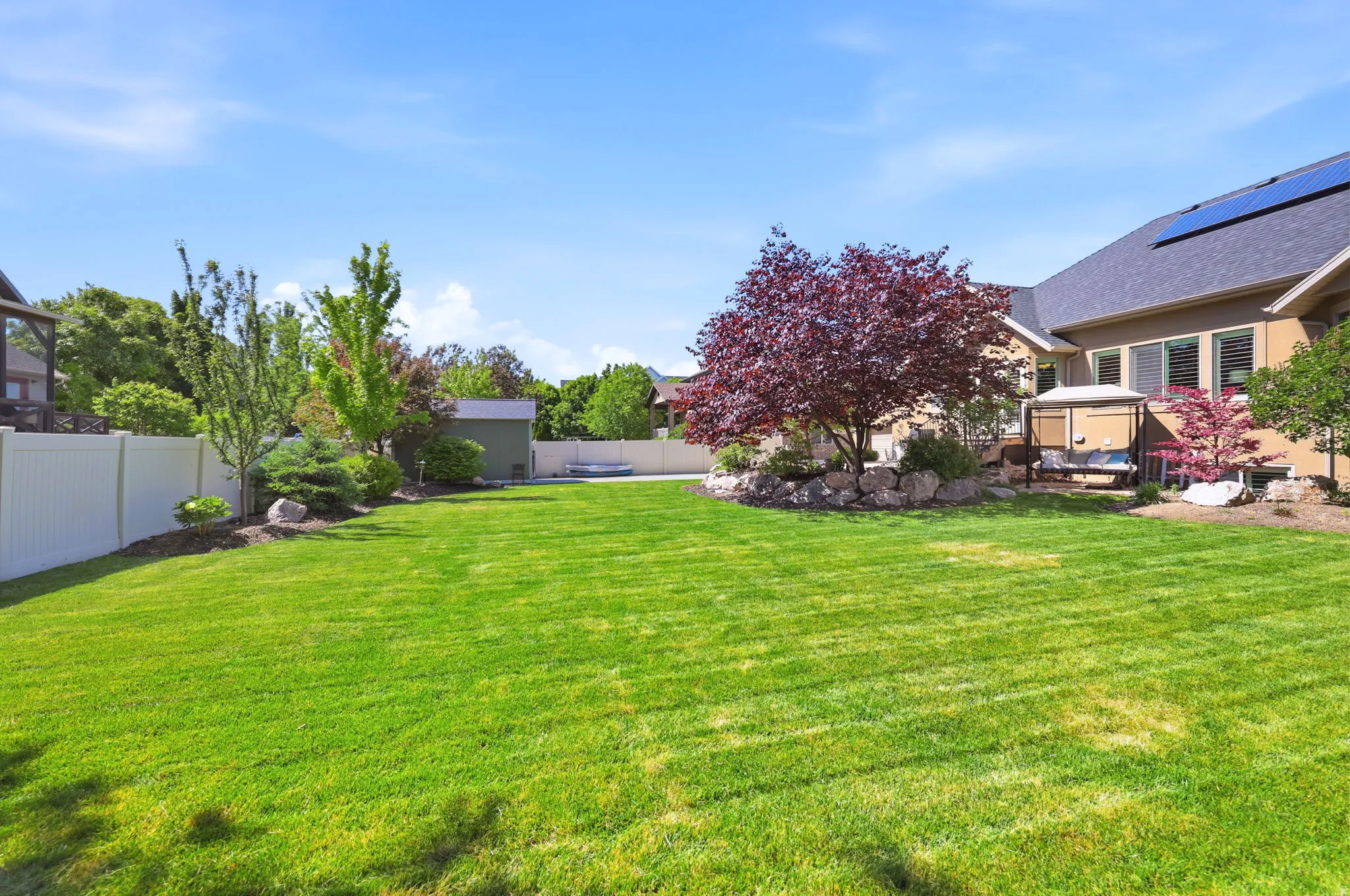 Expansive green lawn with a white privacy fence