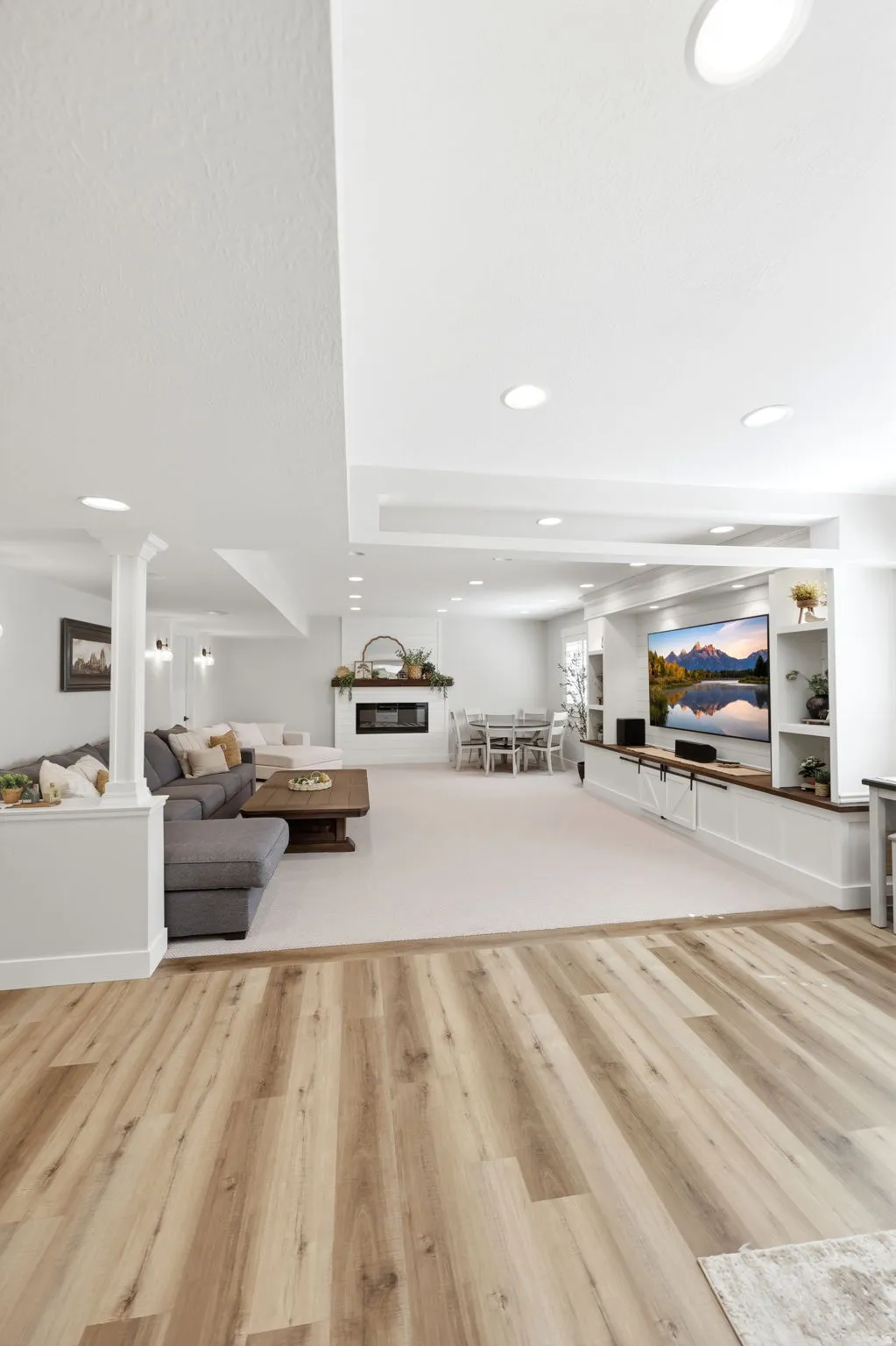 Spacious interior featuring wood-finish flooring, recessed lighting, a built-in media center, a fireplace with a mantel, and a carpeted area